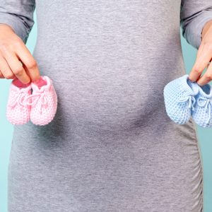 Pregnant woman holding pink and blue baby booties