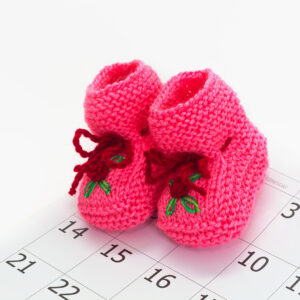 Pink baby booties on a calendar background